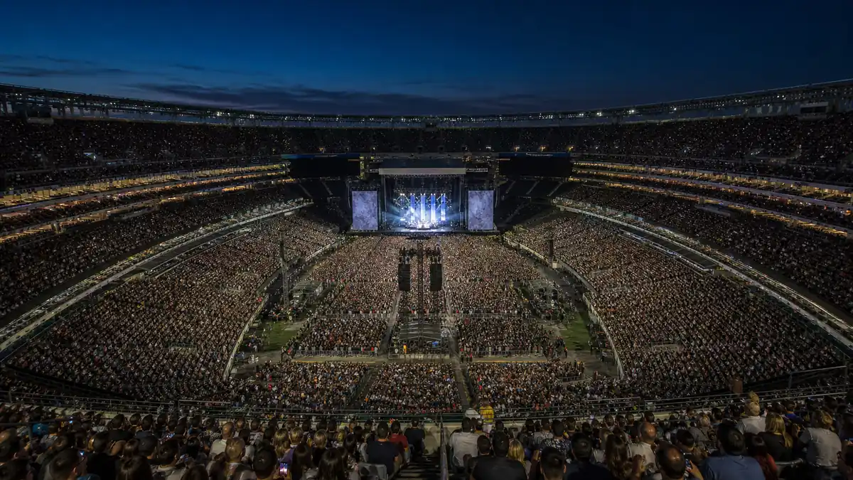 MetLife Stadium concerts 2026 in East Rutherford NJ: an open-air NFL stadium at night with stage lighting visible and a large crowd under a summer evening sky